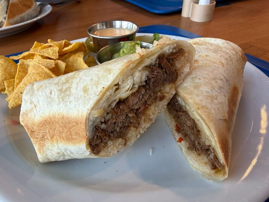 Photo of a beef burrito with nachos and dips